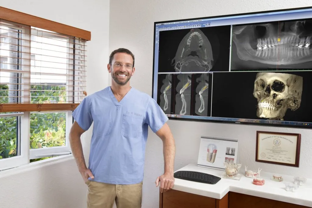 [LAST_NAME] standing and smiling in an exam room